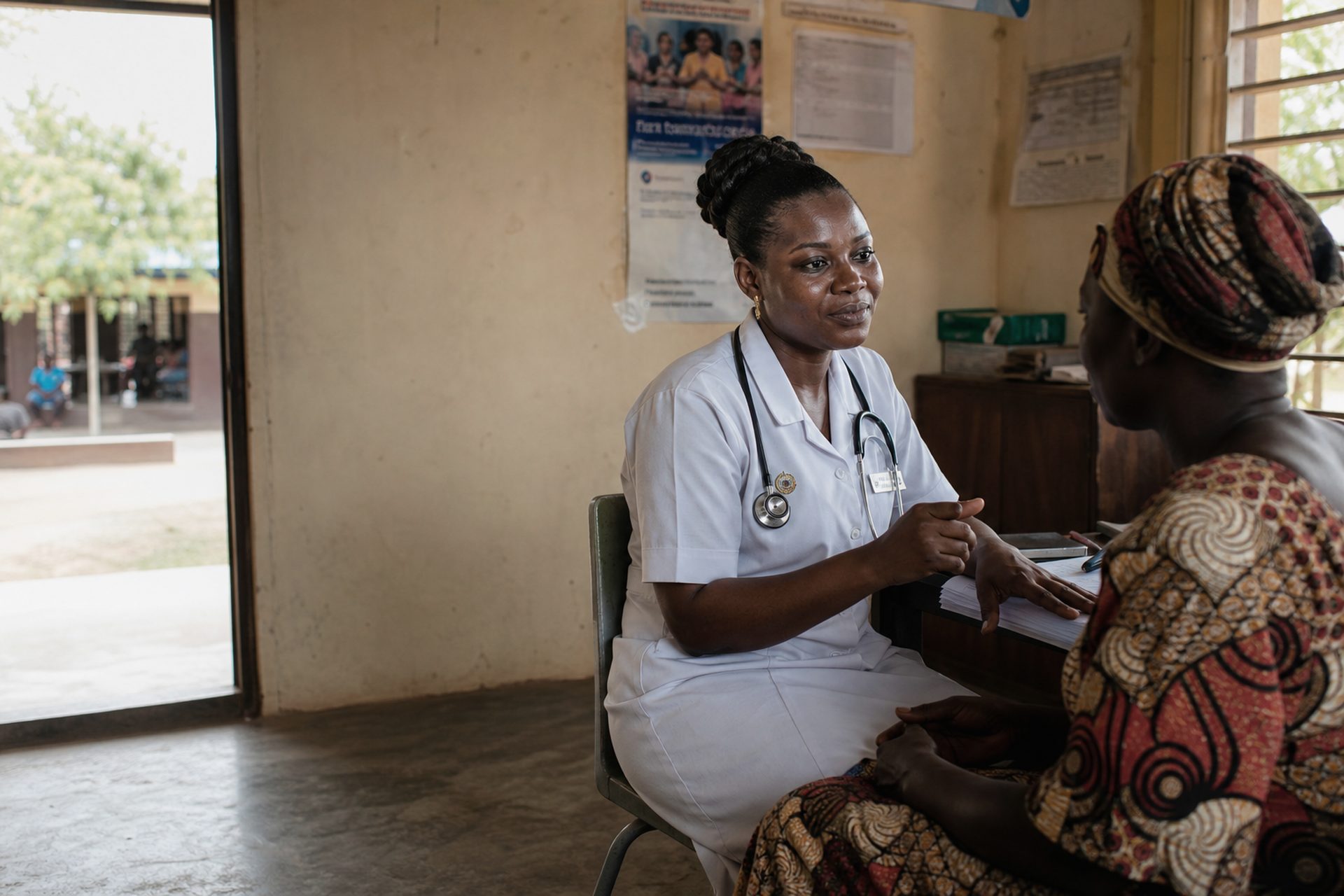 Community health worker in white scrubs caring for a patient in Ghana